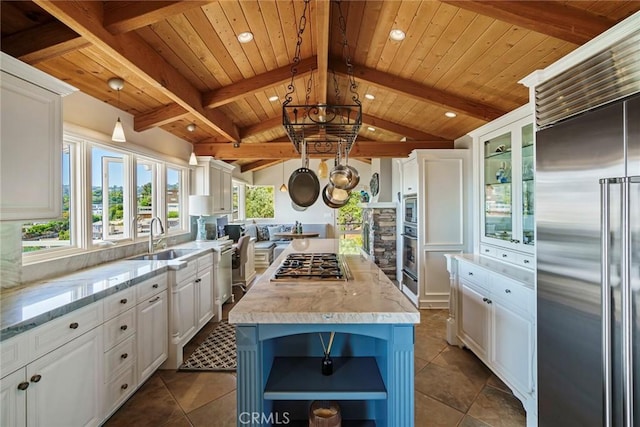 kitchen with sink, white cabinetry, built in appliances, a center island, and pendant lighting