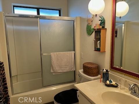 full bathroom featuring enclosed tub / shower combo, vanity, and toilet