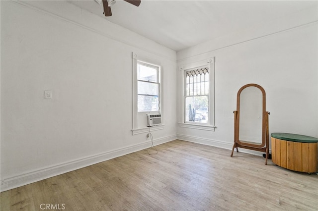 empty room with cooling unit, ceiling fan, and light hardwood / wood-style flooring