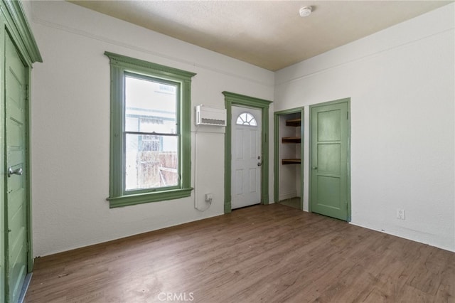 foyer with hardwood / wood-style floors and a wall unit AC