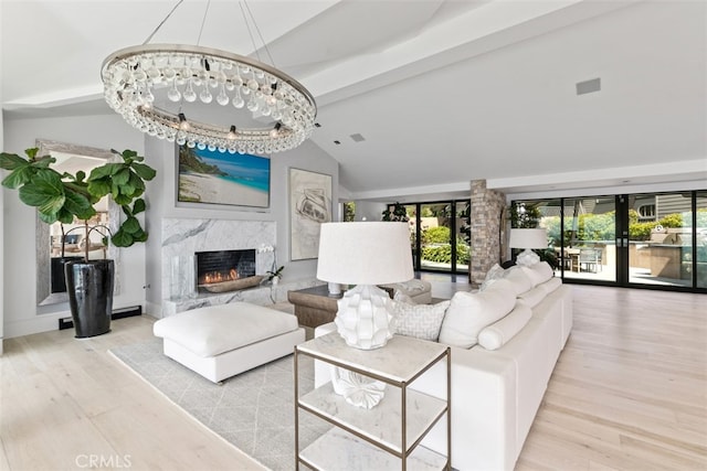 living room with beam ceiling, light hardwood / wood-style flooring, a premium fireplace, and a chandelier