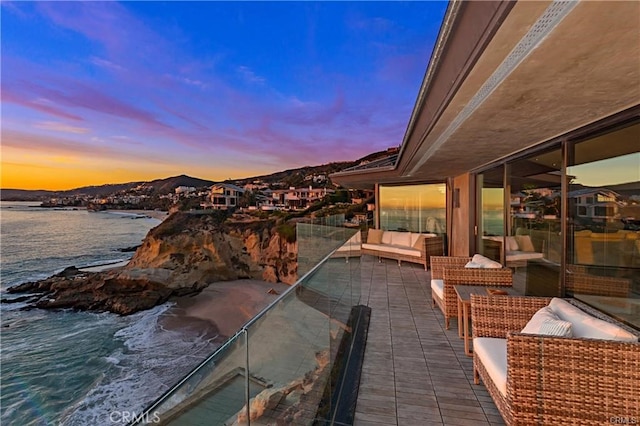 balcony at dusk with an outdoor hangout area and a water view