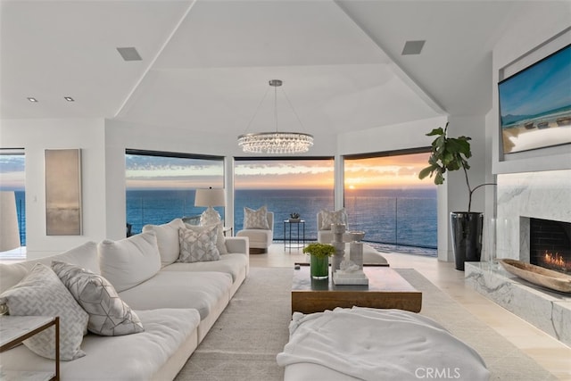 living room with a fireplace, a water view, and a notable chandelier