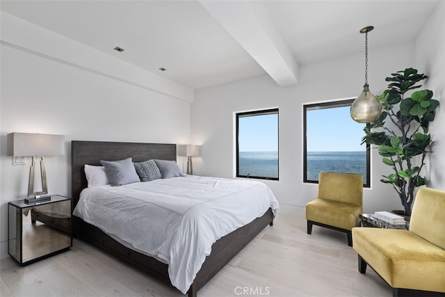 bedroom featuring light wood-type flooring, a water view, and beamed ceiling