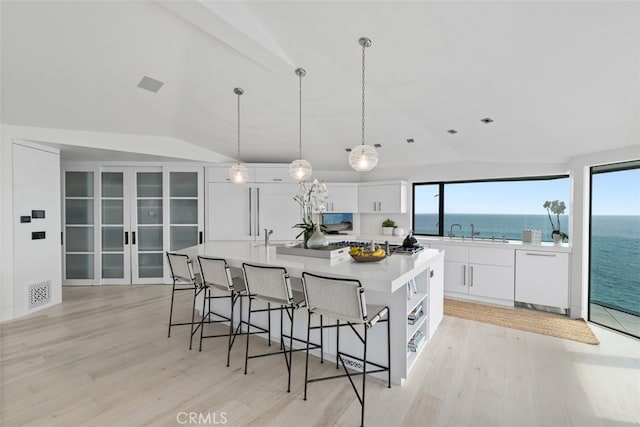 kitchen featuring white dishwasher, a wealth of natural light, a water view, and white cabinetry