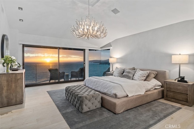 bedroom with access to exterior, a notable chandelier, vaulted ceiling, light hardwood / wood-style flooring, and a water view