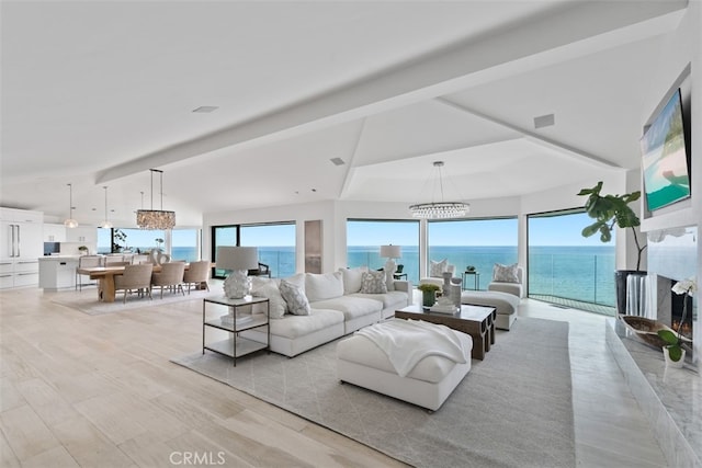 living room with light hardwood / wood-style floors, a water view, beam ceiling, and a notable chandelier