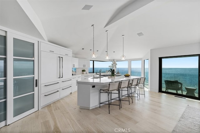 kitchen with decorative light fixtures, a water view, white cabinetry, and a wealth of natural light