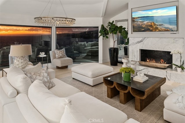 living room with lofted ceiling, a chandelier, a premium fireplace, and light hardwood / wood-style flooring