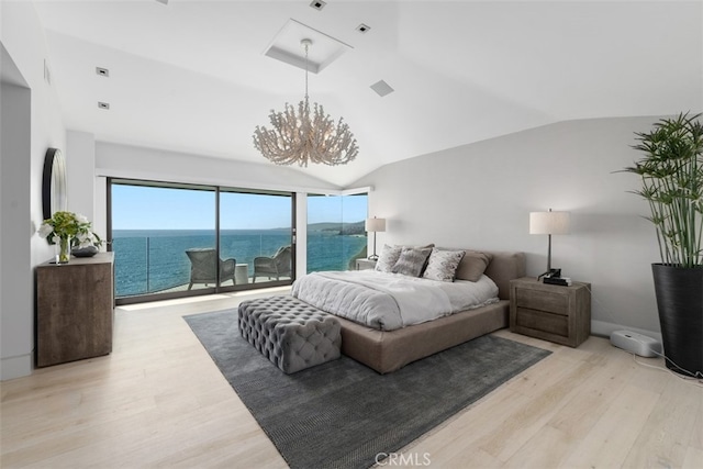 bedroom featuring light wood-type flooring, a water view, vaulted ceiling, and an inviting chandelier