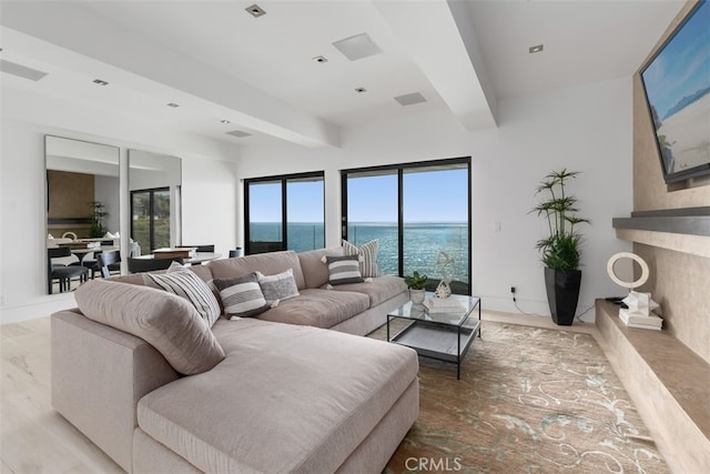 living room with beamed ceiling, light hardwood / wood-style flooring, and a premium fireplace