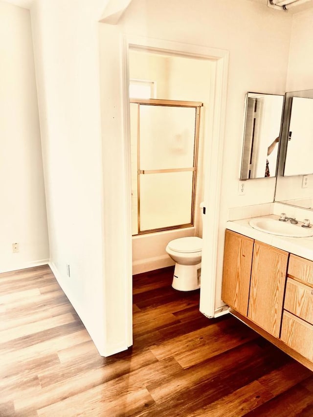 full bathroom with vanity, hardwood / wood-style flooring, toilet, and enclosed tub / shower combo