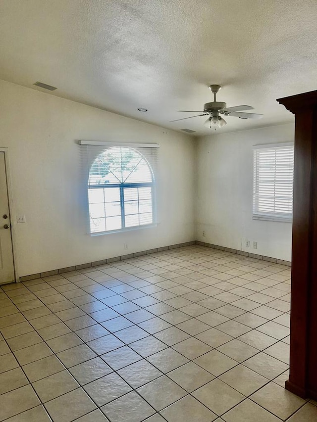 spare room featuring ceiling fan, light tile patterned floors, and a wealth of natural light