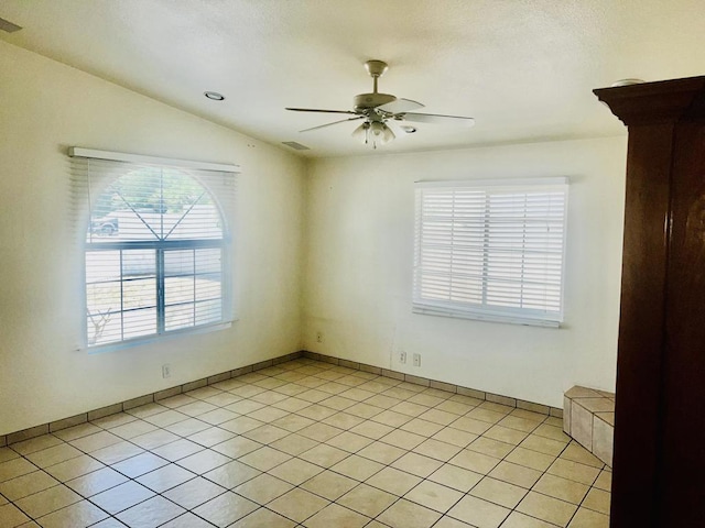 empty room featuring ceiling fan, light tile patterned flooring, a textured ceiling, and vaulted ceiling