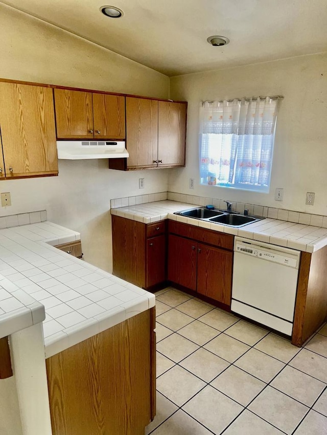 kitchen featuring tile countertops, dishwasher, lofted ceiling, and sink