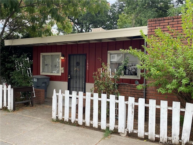 view of front facade with board and batten siding and fence