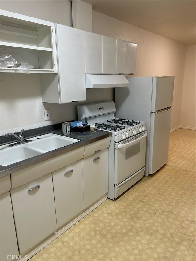 kitchen with under cabinet range hood, light floors, dark countertops, a sink, and white appliances