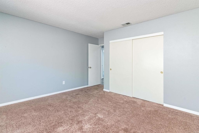 unfurnished bedroom with a closet, a textured ceiling, and carpet