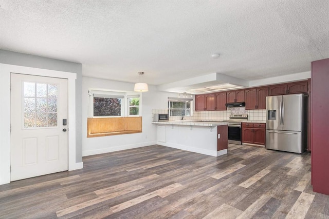 kitchen with decorative light fixtures, dark wood-type flooring, a breakfast bar, and appliances with stainless steel finishes