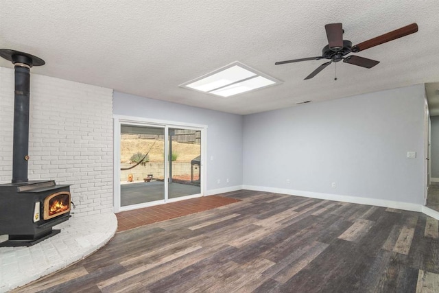 unfurnished living room featuring ceiling fan, dark hardwood / wood-style flooring, a textured ceiling, and a wood stove