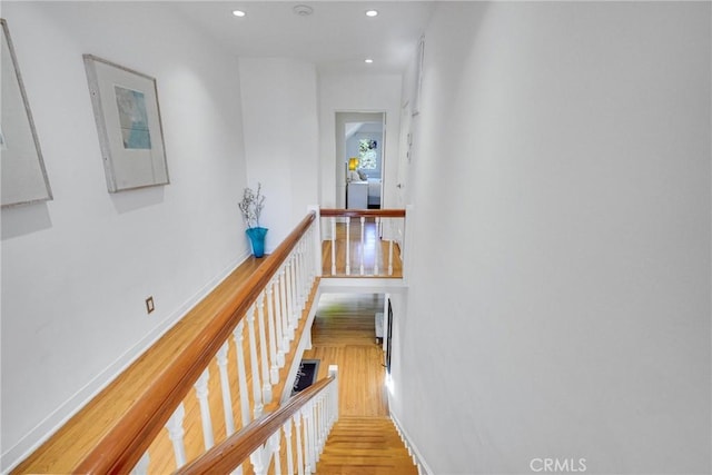 hall with washer / dryer and light hardwood / wood-style flooring