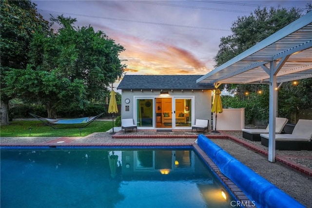 pool at dusk featuring an outbuilding and a pergola