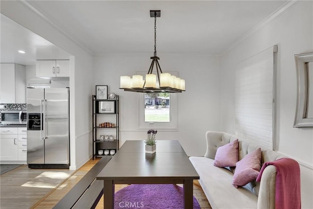 dining area featuring a notable chandelier, light hardwood / wood-style flooring, and ornamental molding