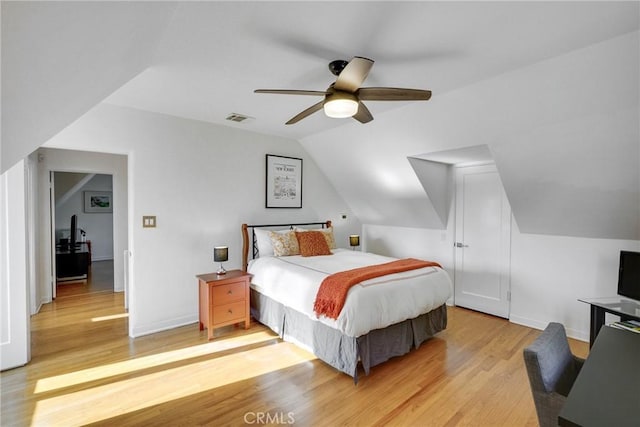 bedroom with ceiling fan, vaulted ceiling, and light wood-type flooring