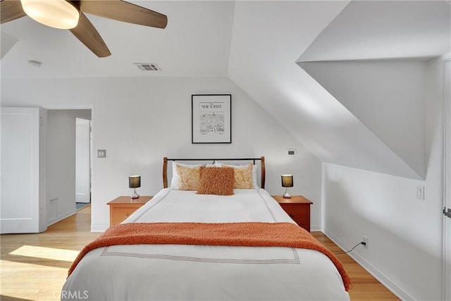 bedroom with ceiling fan, lofted ceiling, and light wood-type flooring