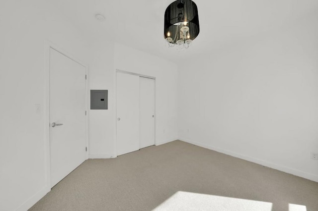 carpeted spare room featuring electric panel and an inviting chandelier