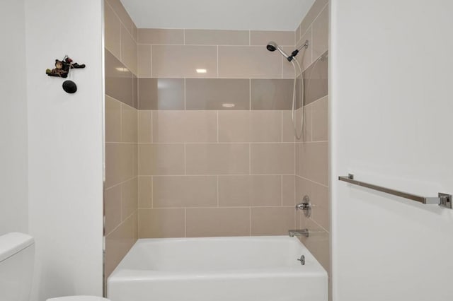 bathroom featuring tiled shower / bath combo and toilet