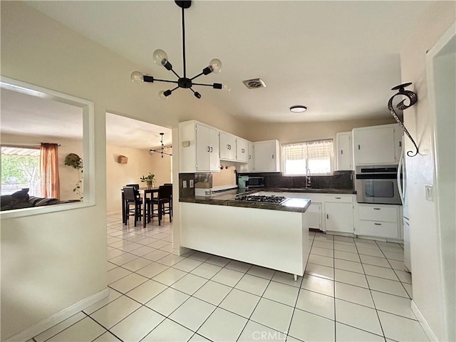 kitchen with appliances with stainless steel finishes, vaulted ceiling, sink, a chandelier, and white cabinetry