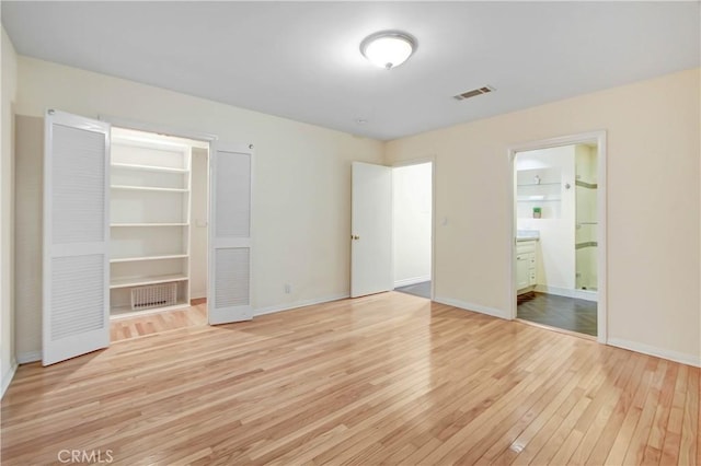 unfurnished bedroom with light hardwood / wood-style floors and ensuite bath