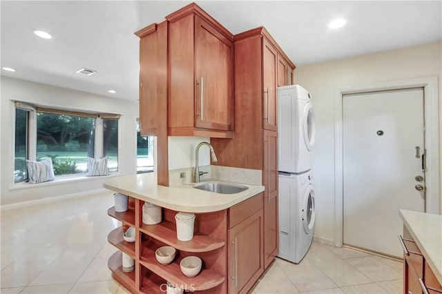 kitchen featuring stacked washer / drying machine, light tile patterned flooring, and sink