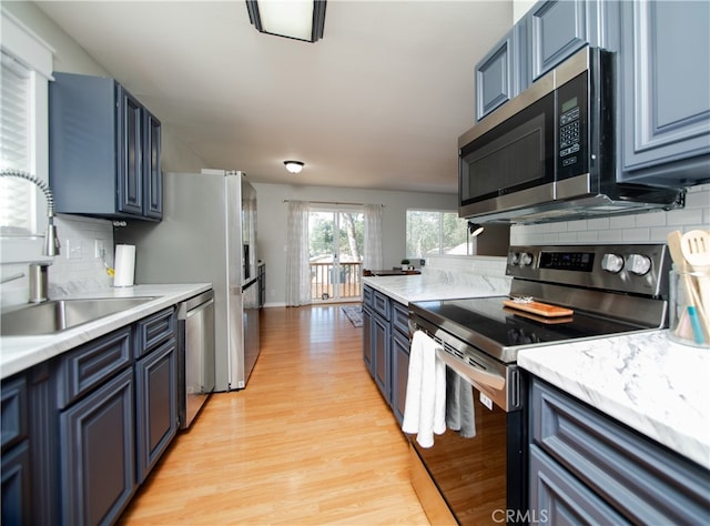 kitchen featuring blue cabinets, stainless steel appliances, and tasteful backsplash