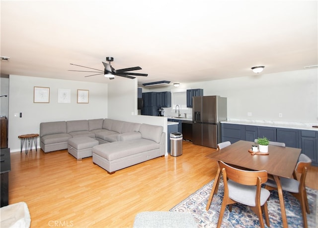 living room with light hardwood / wood-style flooring, ceiling fan, and sink