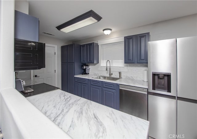 kitchen with decorative backsplash, blue cabinets, appliances with stainless steel finishes, and sink