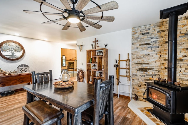 dining room with a wood stove, light hardwood / wood-style floors, and ceiling fan