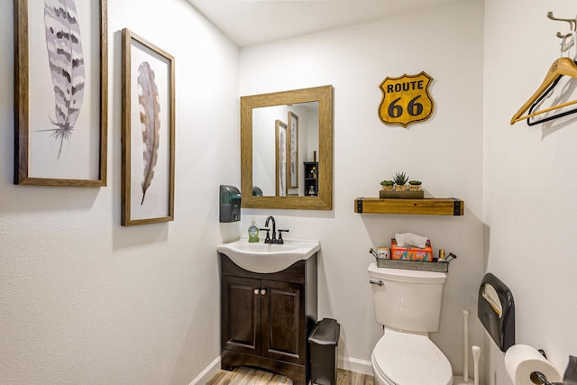 bathroom with hardwood / wood-style floors, vanity, and toilet