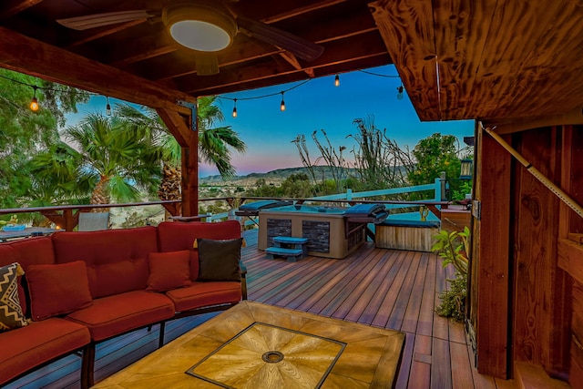 deck at dusk with outdoor lounge area and ceiling fan