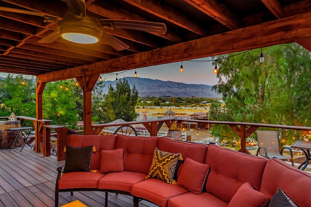 deck at dusk featuring a mountain view, ceiling fan, and outdoor lounge area