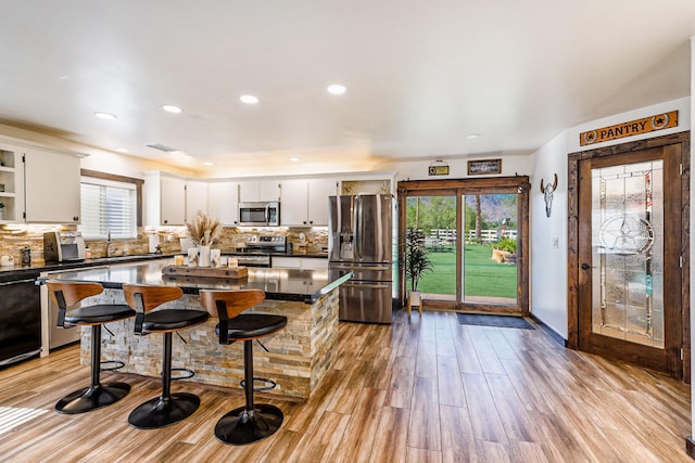 kitchen featuring white cabinets, stainless steel appliances, light wood-type flooring, and a wealth of natural light