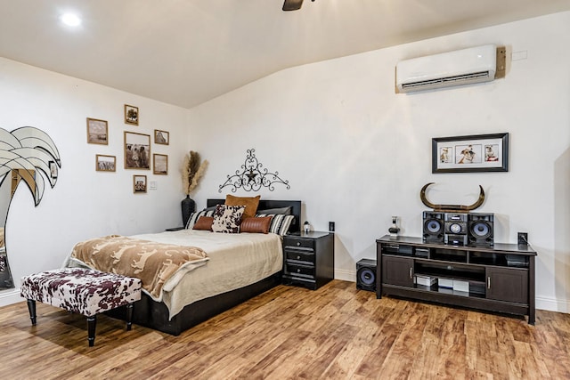 bedroom with wood-type flooring, lofted ceiling, a wall unit AC, and ceiling fan