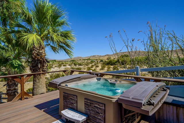 deck with a hot tub and a mountain view