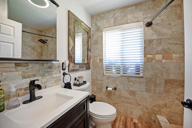 bathroom featuring vanity, tasteful backsplash, tiled shower, hardwood / wood-style flooring, and toilet