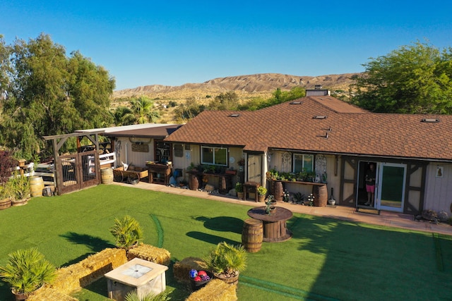 back of house with a patio, a mountain view, and a yard