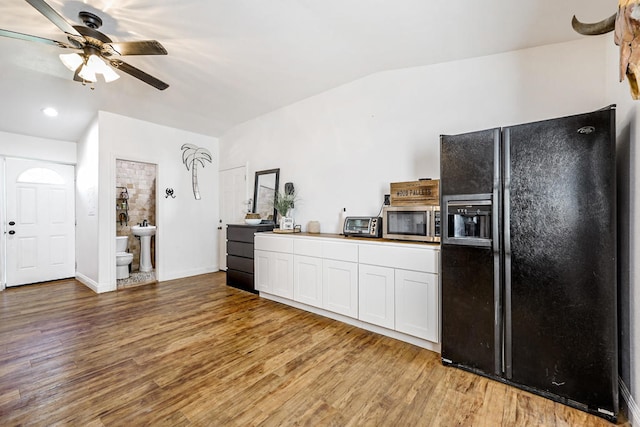 kitchen featuring white cabinets, ceiling fan, hardwood / wood-style flooring, and black fridge