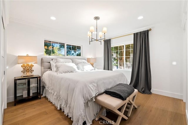 bedroom with crown molding, baseboards, a chandelier, and light wood finished floors