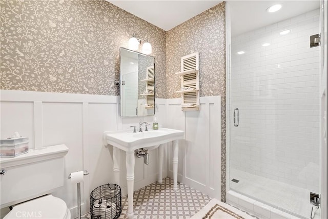 bathroom with wainscoting, toilet, tile patterned floors, wallpapered walls, and a shower stall