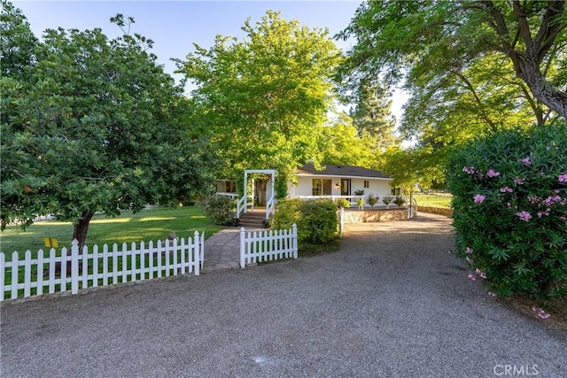 obstructed view of property featuring fence private yard and a front lawn